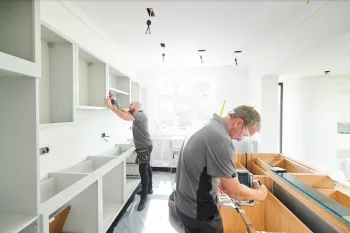 Two men installing kitchen cabinets in a bright home renovation project